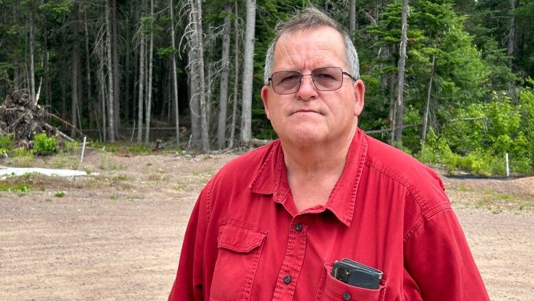 A white man with white hair, glasses, wearing a red shirt.