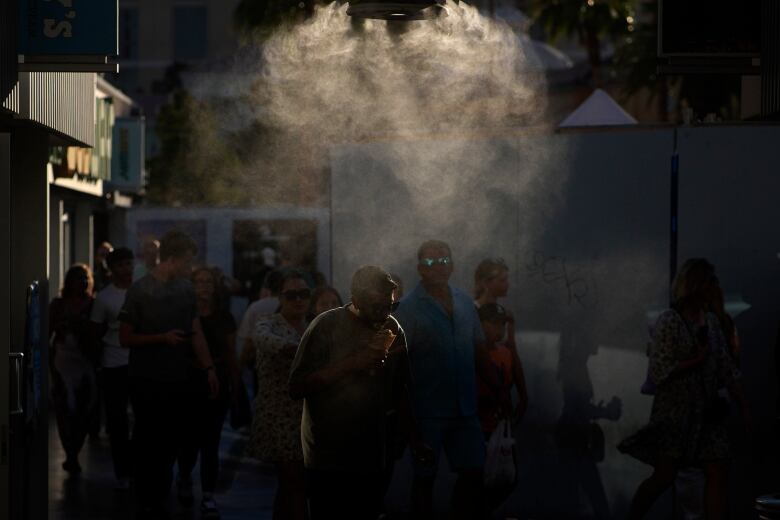 People walk through misters along the Las Vegas Strip in Las Vegas. The city set an all time record high of 48.8 C as a heat wave spread across the Western U.S. sending many residents in search of a cool haven from the dangerously high temperatures.