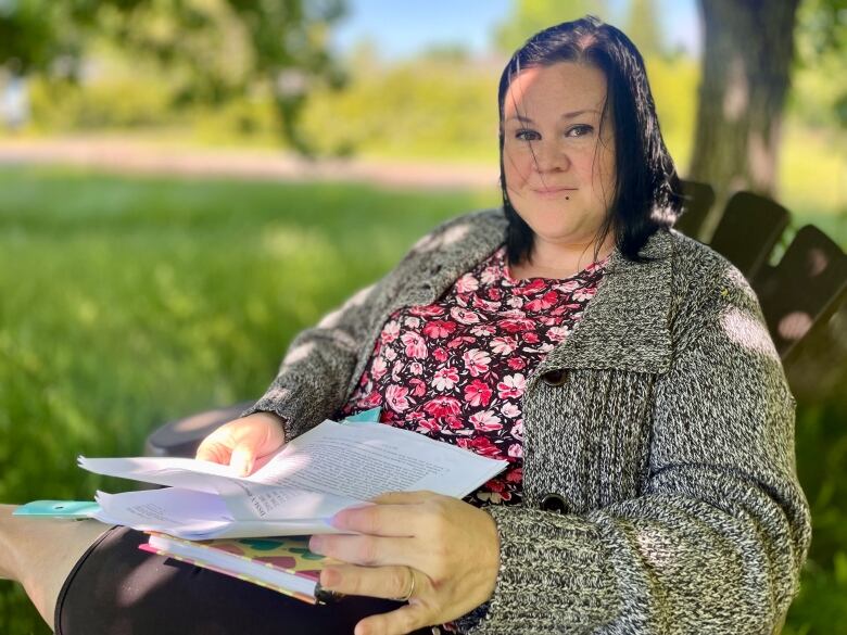 Shirley-Ann Muncey sits in a chair outside, holding a child psychologist's reporr.