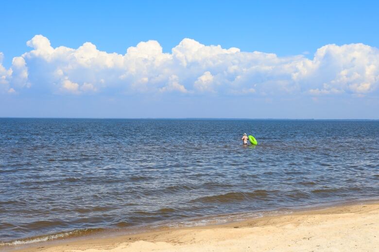 A man swims at a beach. 