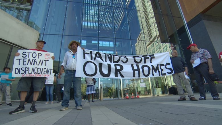 Two men holding a banner that reads 