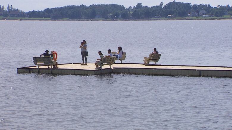 People standing and sitting on dock in water/