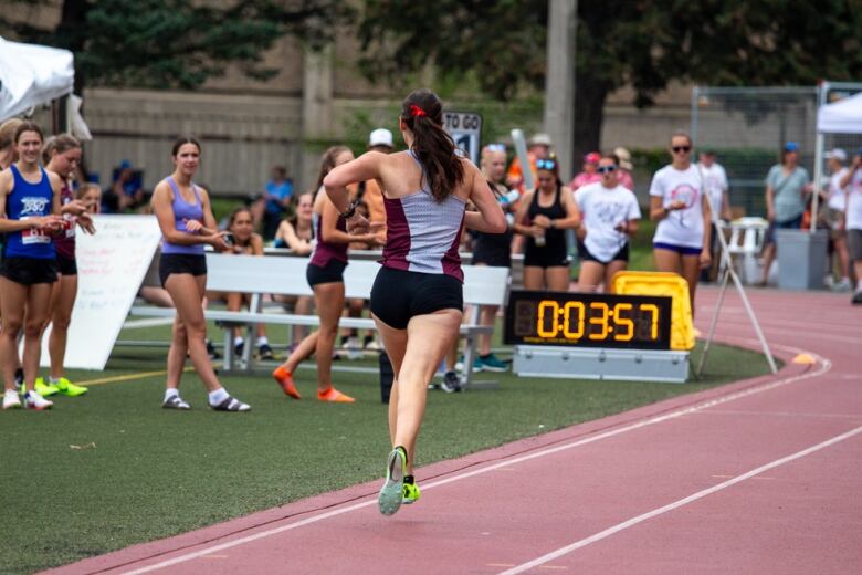 A runner on a track approaches a finish line while people watch and cheer.