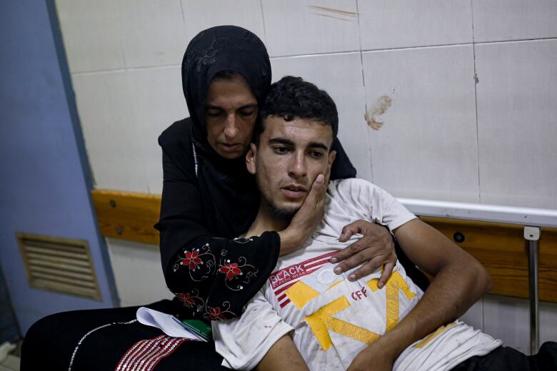 A woman hugs  a man in a hospital  corridor