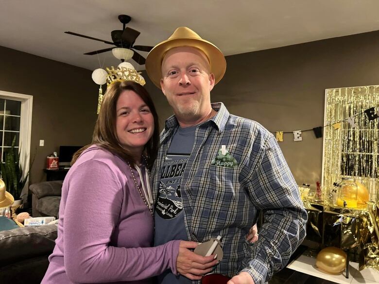 A woman and man wearing New Year's hats in a living room