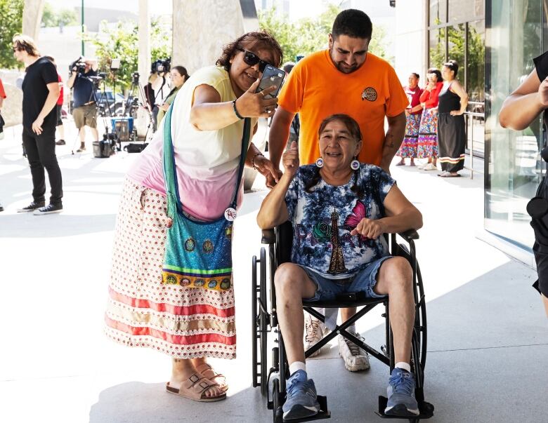 A woman in a wheelchair smiles with two other people.