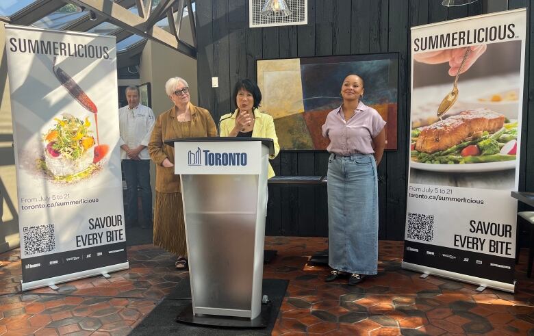 Mayor Olivia Chow stands behind a podium and takes questions from reporters.