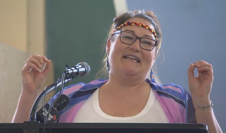 A woman with a headband speaks at a microphone