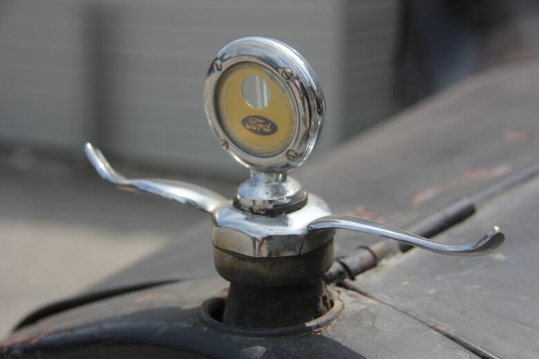 The brass and silver hood ornament of a car, with the name 