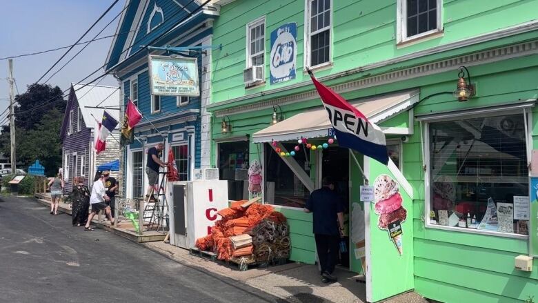 people gather in front of and walk into colourful buildings 