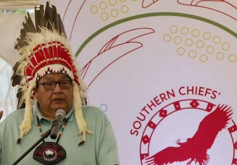 A man stands wearing a war bonnet.