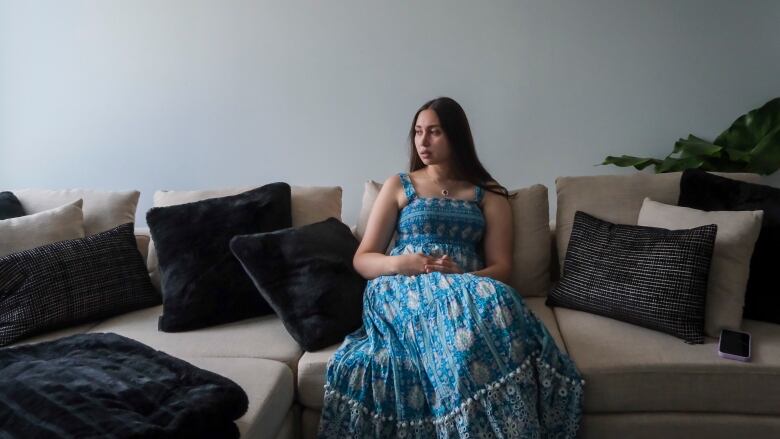 Raffaela Cruz sitting on her couch in her apartment.