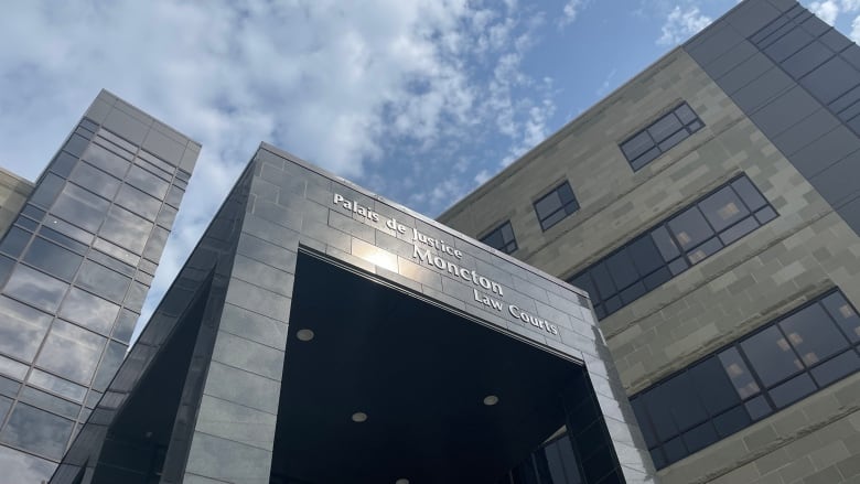 The sun shines on the main sign on the Moncton Law Courts building. The sign reads, Palais de Justice Moncton Law Courts.