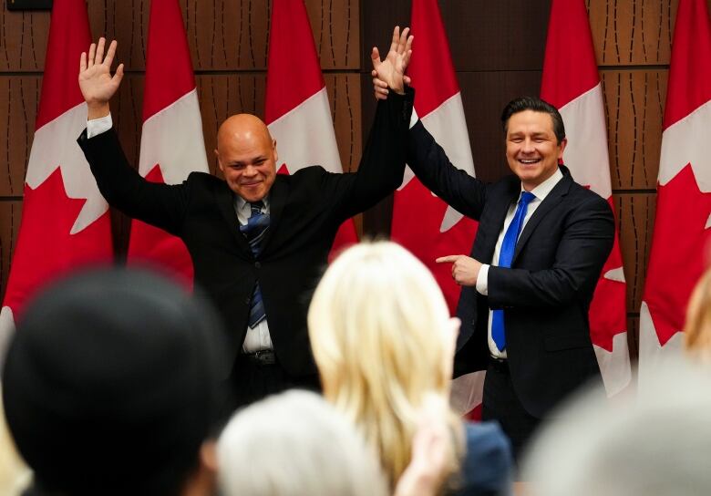 Conservative Leader Pierre Poilievre raises the hand of newly-elected Conservative member of Parliament Jamil Jivani as he introduces him at a caucus meeting on Parliament Hill in Ottawa on Wednesday, March 20, 2024.