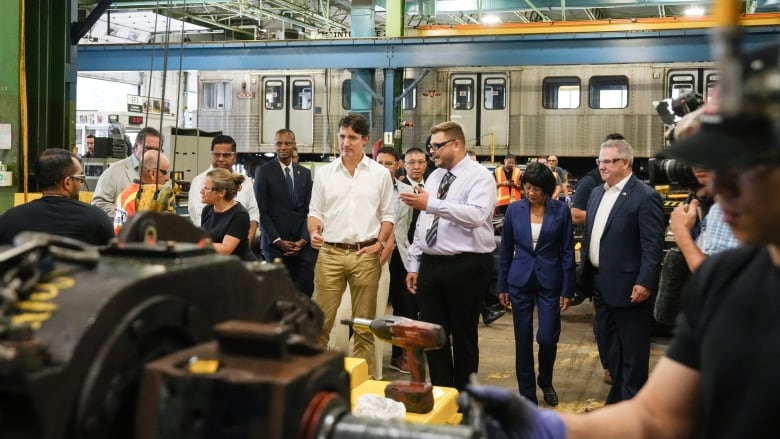 Multiple people stand and look at unused transit cars in Toronto.