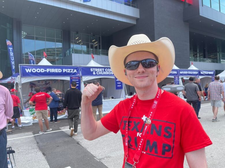 A young man wearing a cowboy hat and a red shirt that reads 