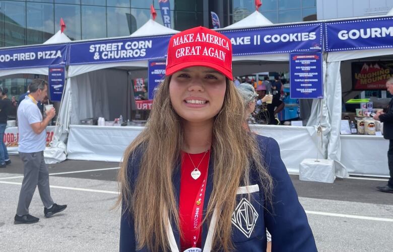 A woman wears a red Make America Great Again hat.