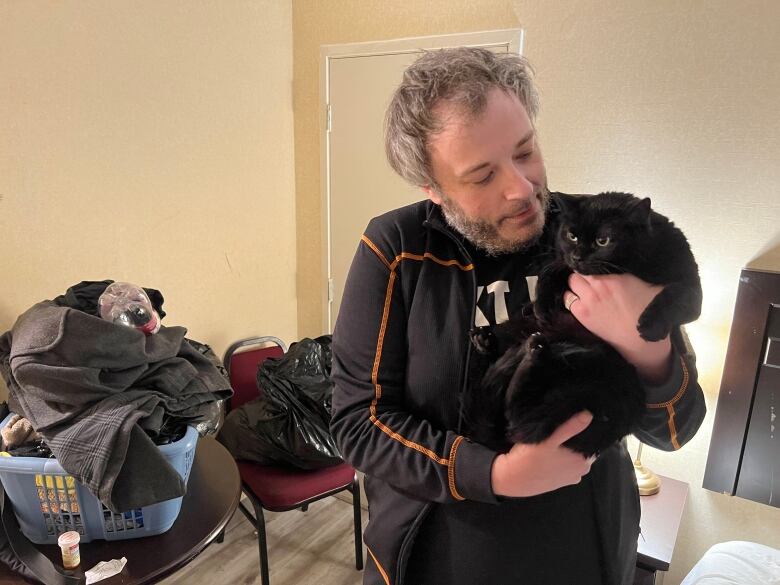 A man in a hotel room holds a cat.