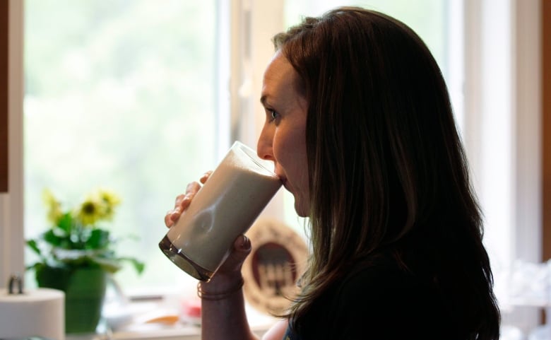 In this 2012 photo,  a woman drinks a protein shake for lunch at her home. She blends a vegan protein powder with almond milk, natural peanut butter, ice and a banana as a drink in her daily diet. 