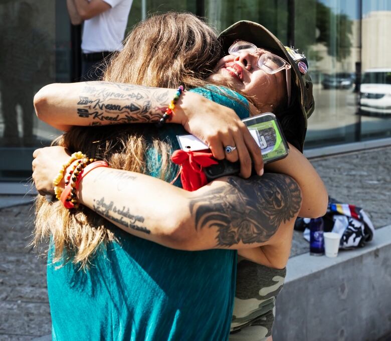 Two people in an emotional embrace outside a courthouse.