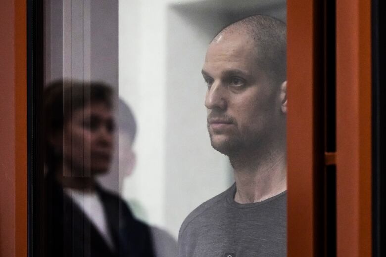 A man looks  through a glass enclosure