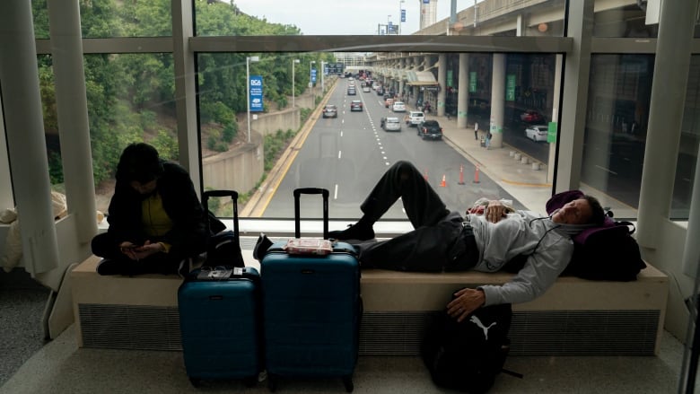 A man sleeps on a window ledge over a street