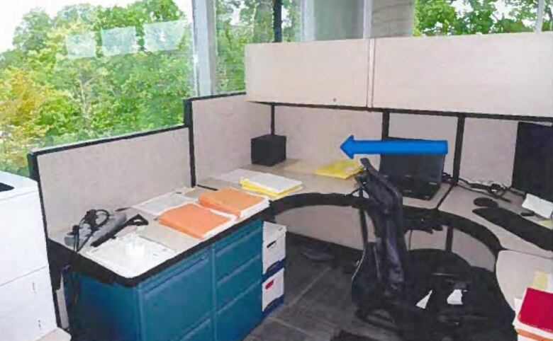 A black box sitting on a desk in a cubicle.