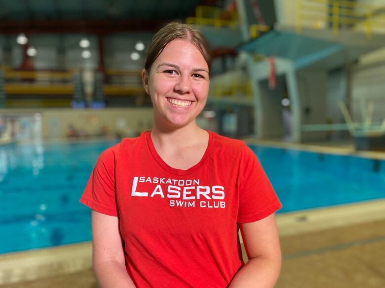 A woman in a red Lasers shirt sits in front of a pool