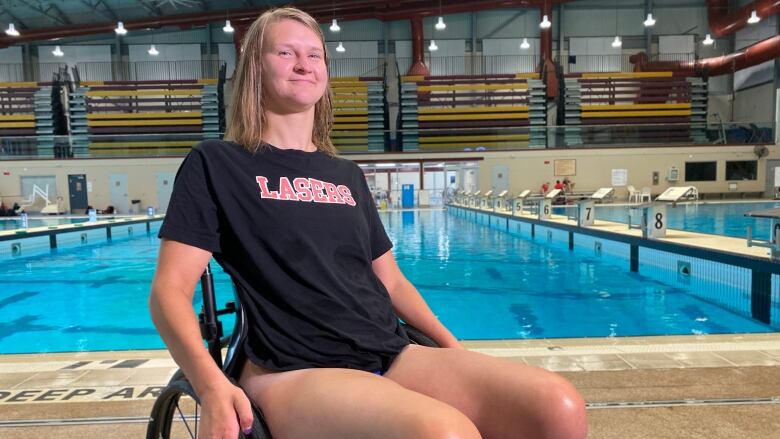 A woman in a wheelchair sits in front of a pool. 