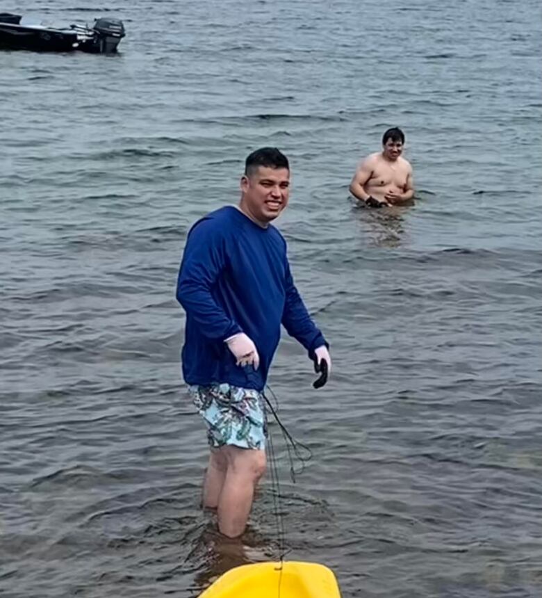 Man in blue T-shirt and shirtless man in water 