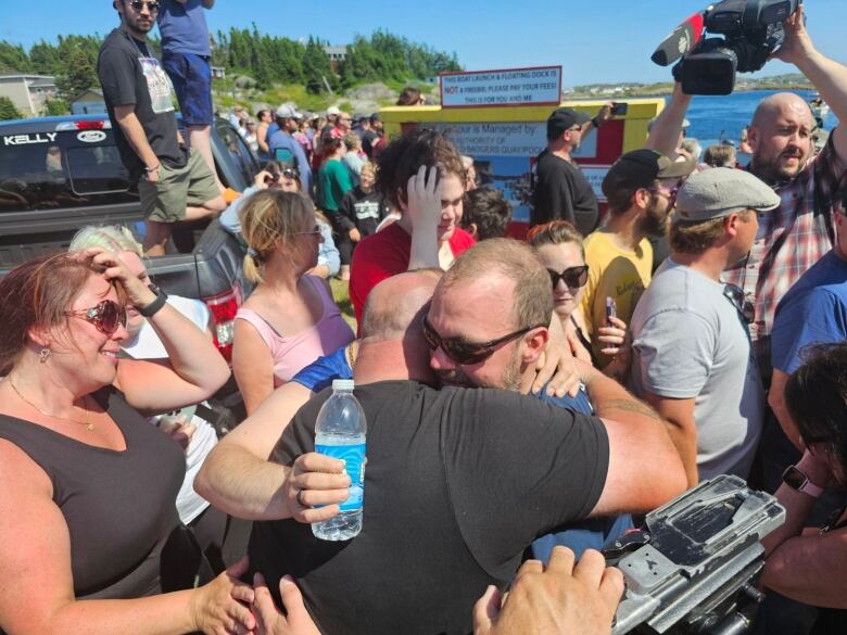 Two men hugging in a crowd of people.