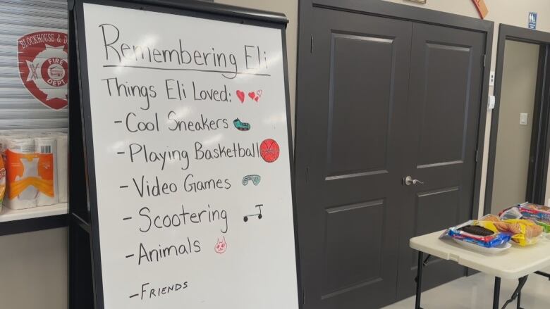 A whiteboard shows a list of things that Eli loved including, cool sneakers, playing basketball, video games, scootering, animals and friends.