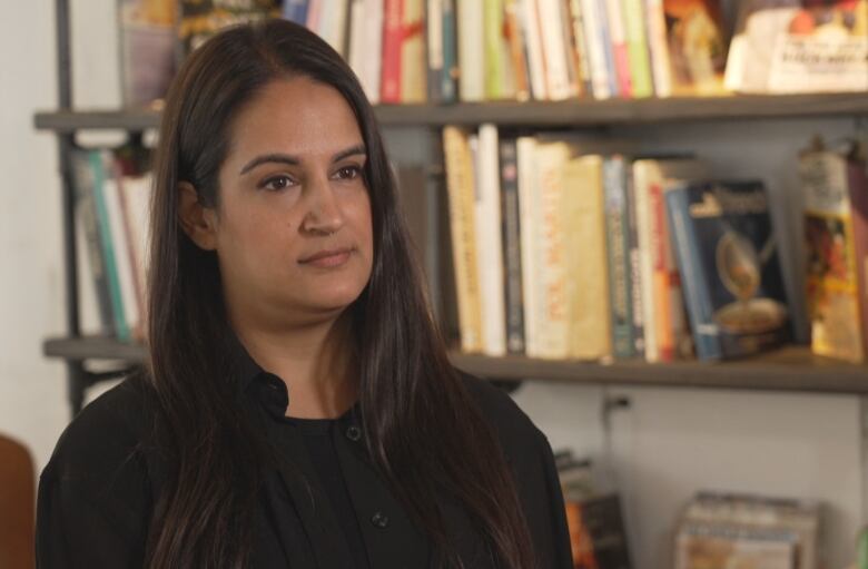 A woman poses in front of a bookshelf in her office.