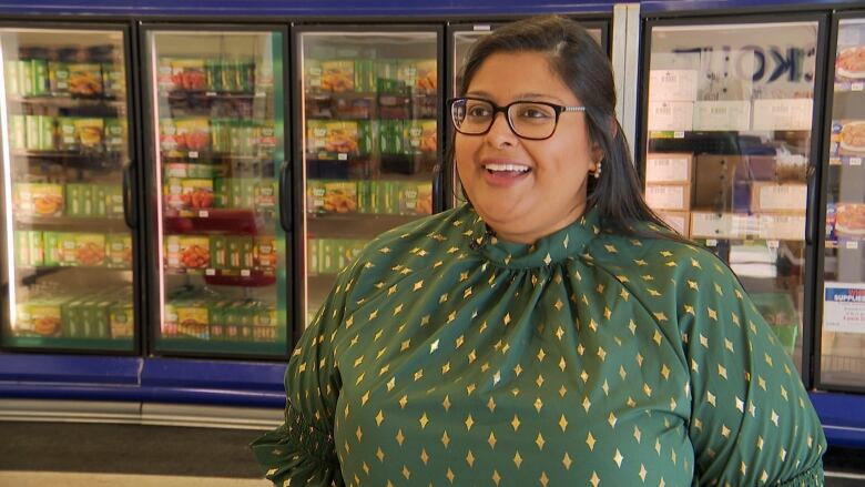 A woman poses in front of a row of freezers holding frozen chicken products.