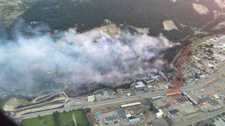 Flames rise from a hill next to a town.