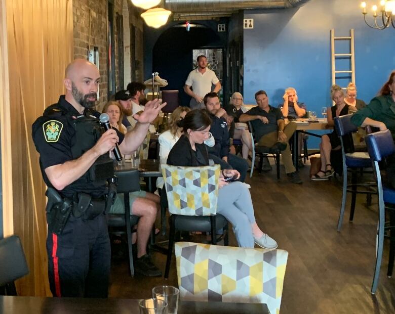 Man in police uniform speaking to group of people. 