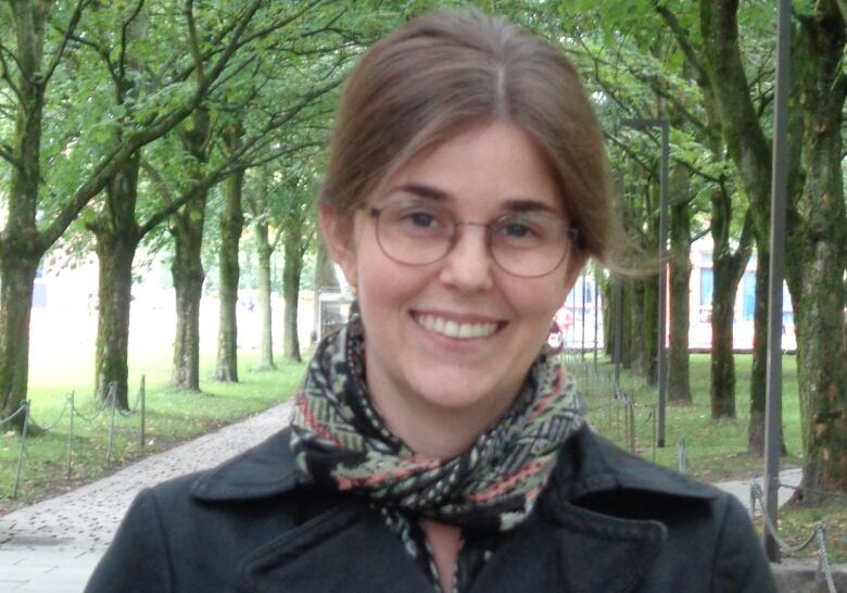 Woman with brown hair, glasses in black coat. 