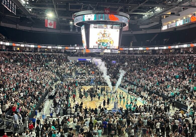 Inside of an arena at a basketball game with thousands of fans.