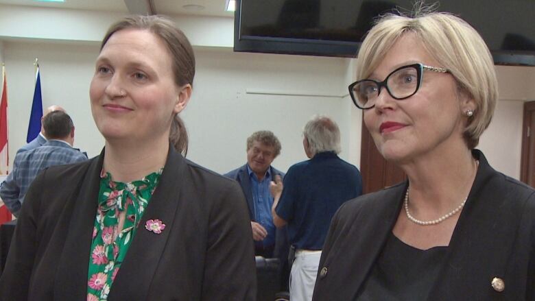 Two women in black suits.