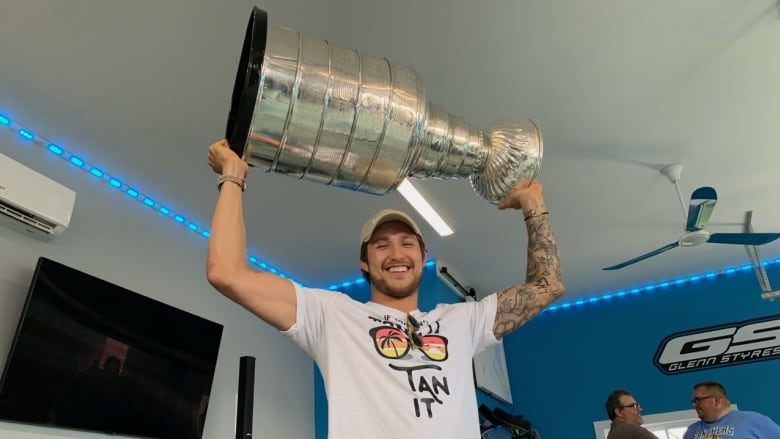 A man holds a big silver trophy over his head. 