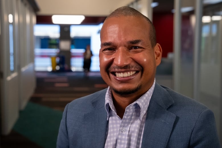 A man wearing a light blue suit smiles.