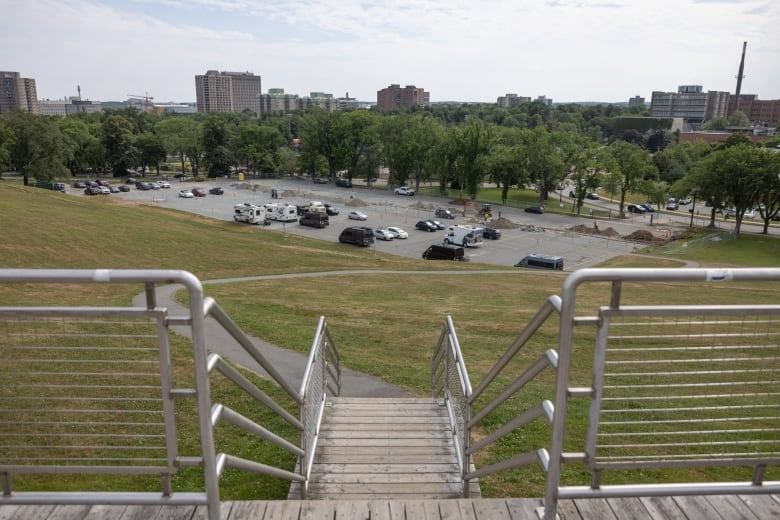 Steps lead to a path heading toward a parking lot with multiple cars parked.