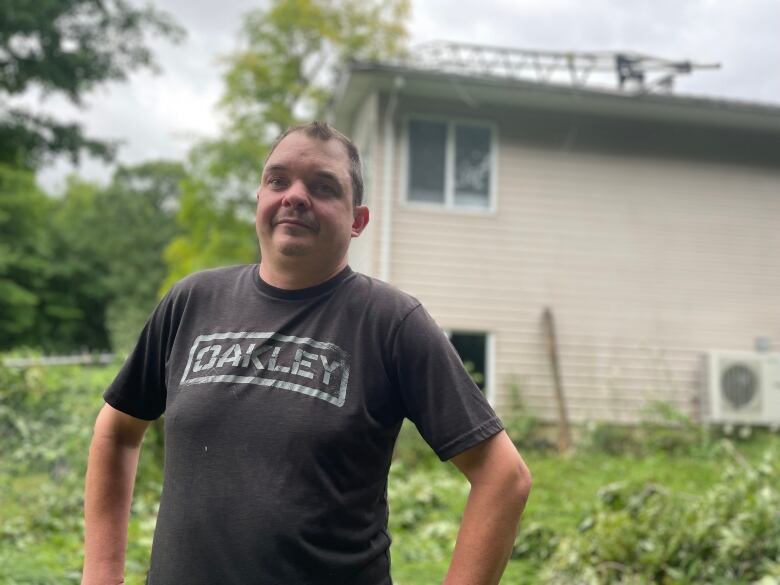 A man stands in front of trees knocked down by intense winds 