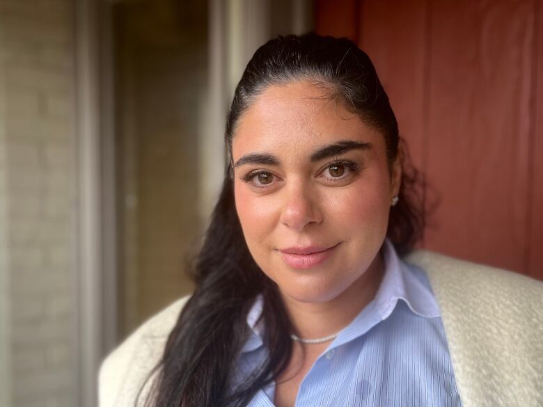 A woman in a blue dress shirt smiles for the camera.