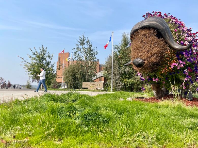 A statue of a bison with flowers on it.