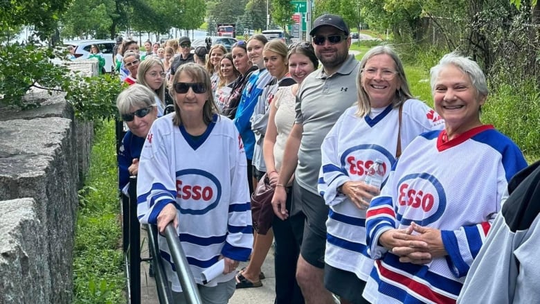 A large group of people wearing hockey jerseys stand outside.