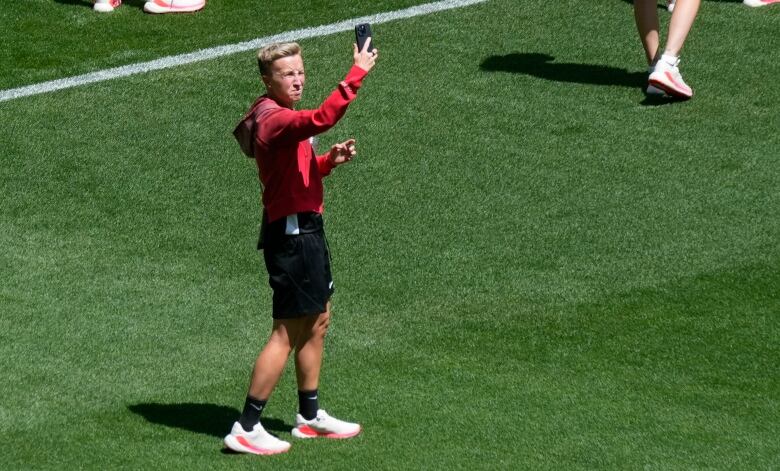 A women's soccer coach holds up her phone.