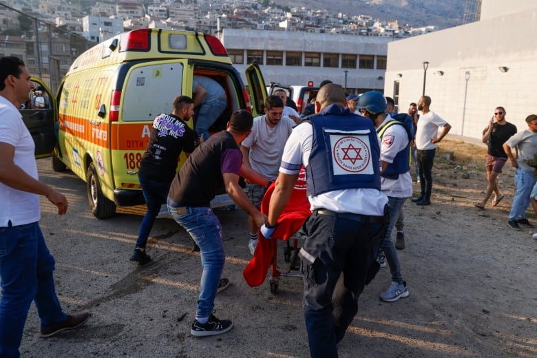 People direct a person on a stretcher toward an ambulance.