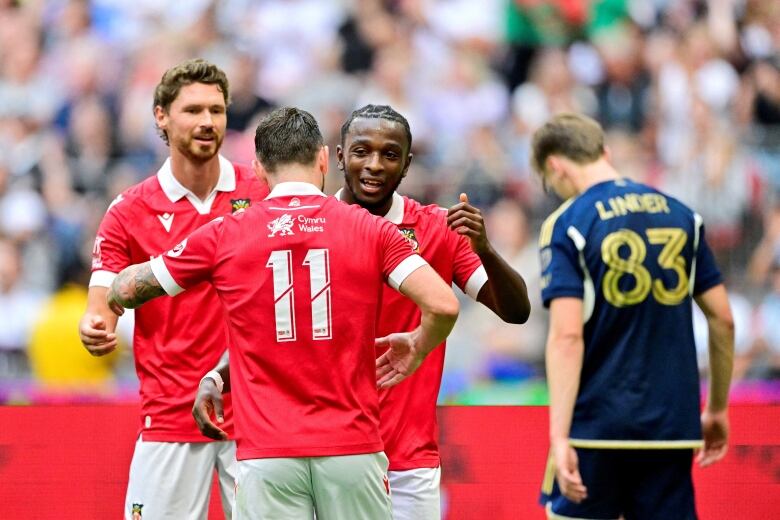 Three soccer team mates hug it out after celebrating a goal. 