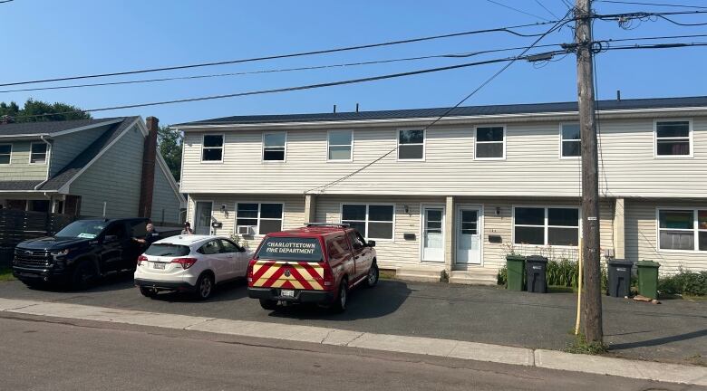 Fire truck parked outside yellow townhouse.